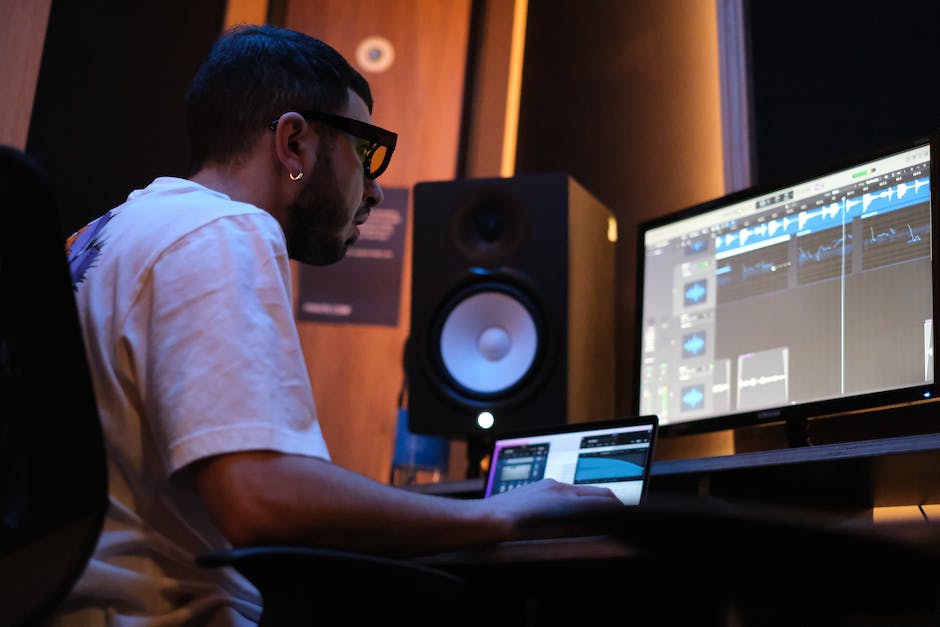 Man Working  in White Shirt Sitting in Front of a Monitor and Speaker